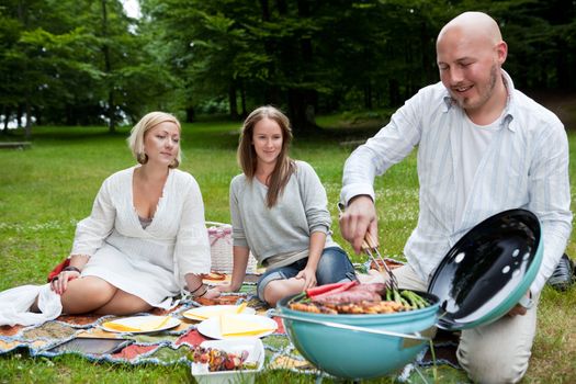 Group of friends barbecuing in park - shallow depth of field, focus on women
