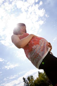 Happy pregnant woman outdoors in park - photo taken against sun with backlight and lens flare