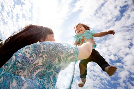 Happy exciting young daughter being thrown into sky by mother