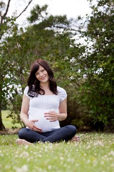 Portrait of an attractive pregnant woman sitting outdoors in park