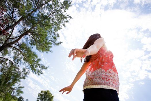 Happy pregnant woman with arms back looking into sky