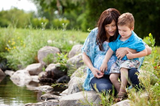 Happy portrait of a mother and son playing by a lake in a park