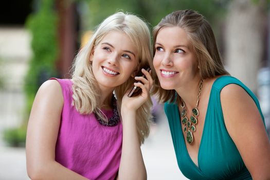 Happy young female friends using a mobile phone