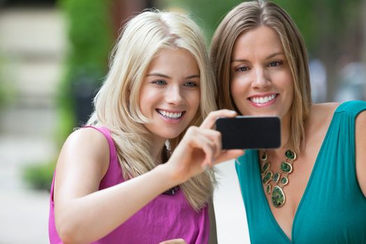 Happy young female friends taking selfportrait with cellphone