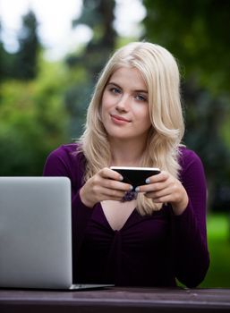 Portrait of beautiful young woman writing status update with smart phone in park