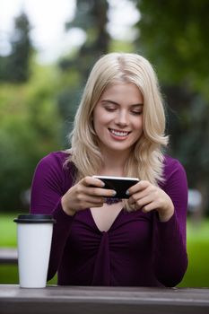 Happy smiling young woman using mobile phone in park
