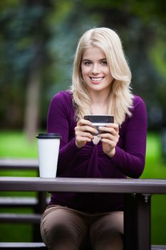 Young college student in park with phone and coffee