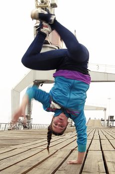 Young female breakdancing doing a handstand with one hand