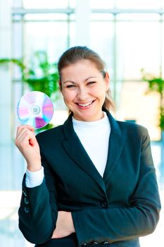 Happy brunette woman holding a CD on blurred background office