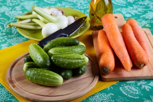 Green cucumbers with onions garlic and carrots on a kitchen table