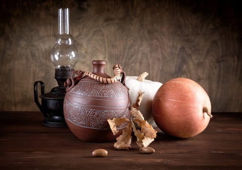 Still-life with a jug an oil lamp and pumpkins on a table