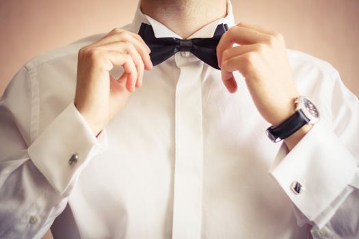 Closeup of business man adjusting neck bow over brown background