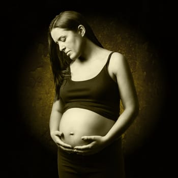 Beautiful pregnant woman looking her belly over a dark background