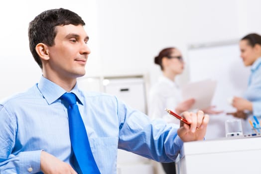 Portrait of a businessman in a blue shirt in the background of colleagues discussing