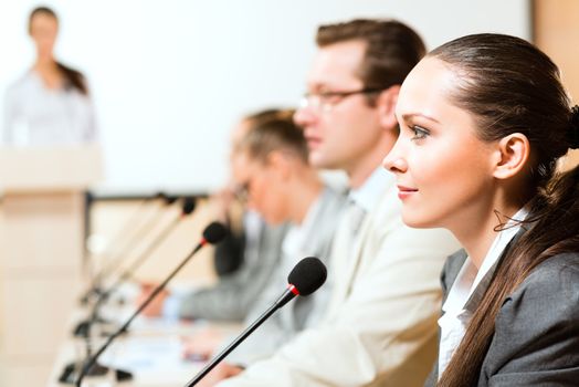 businessmen communicate at the conference, sitting at the table, on the table microphones and documents