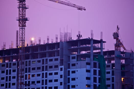 Industrial construction cranes and building at twilight
