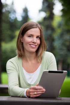 Woman holding Digital Tablet in park.