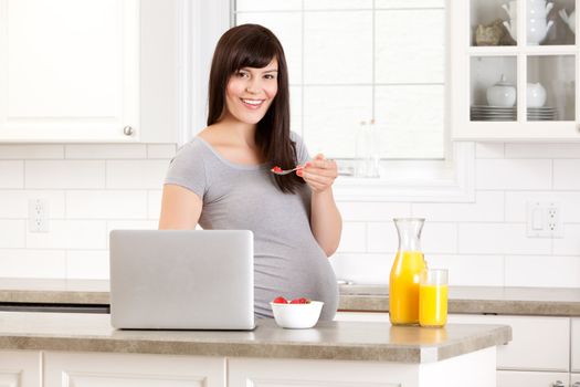 Pregnant woman in kitchen looking at camera, eating breakfast