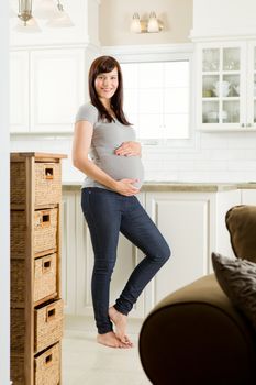 Portrait of a beautiful and healthy pregnant woman standing in kitchen