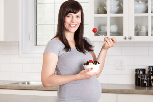 Pregnant woman eating a healthy snack at home in kitchen