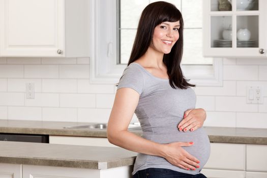 Portrait of healthy happy pregnant woman standing in kitchen.