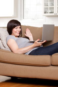 Happy pregnant woman talking on internet video chat