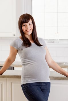 Portrait of a beautiful pregnant woman standing in kitchen