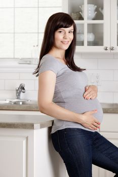 Vertical portrait of pretty pregnant woman at home in kitchen