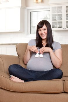 Portrait of a beautiful young pregnant woman holding baby shoes