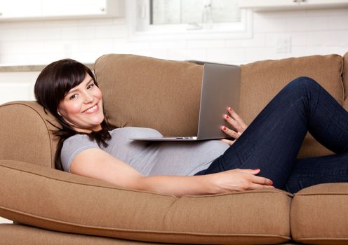 Relaxed happy pregnant woman sitting on sofa with laptop computer