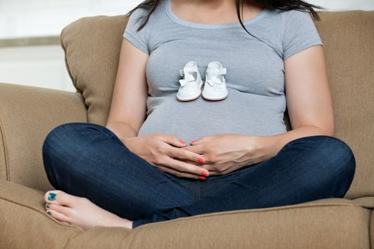 Low section of pregnant woman with baby shoes on her belly