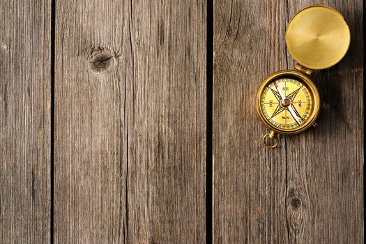 Antique brass compass over wooden background