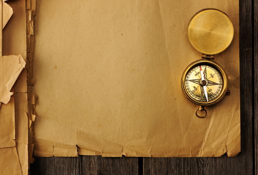 Antique brass compass over old paper background