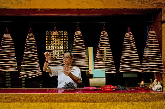 man lighting incense in chinese temple ho chi minh vietnam