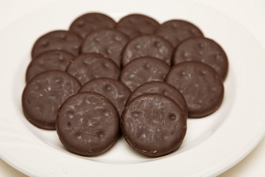 A white plate full of thin, chocolate covered mint cookies