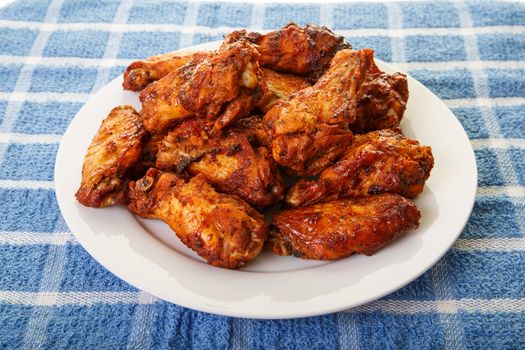 A white plate of spicy, mesquite flavored chicken wings