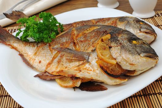 Dorado baked fish with lemon on a plate close-up