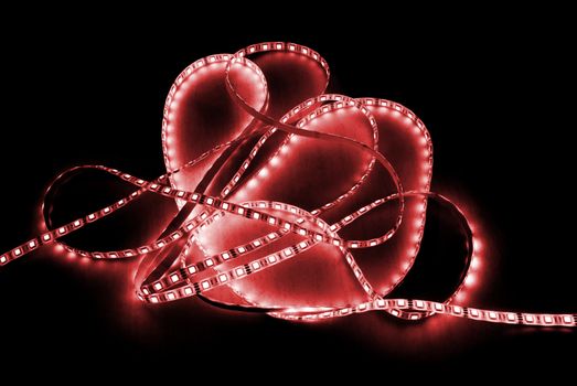 red led strip with a glue layer, background in the dark, illuminated by strip