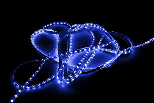 blue led strip with a glue layer, background in the dark, illuminated by strip