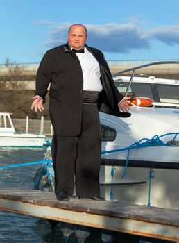 Overweight man in tuxedo standing on the deck of a luxury pleasure boat