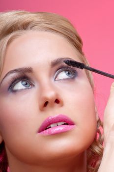 Beautiful woman applying mascara on her eyelashes