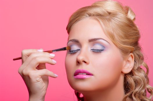 Beautiful young woman applying cosmetic paint brush
