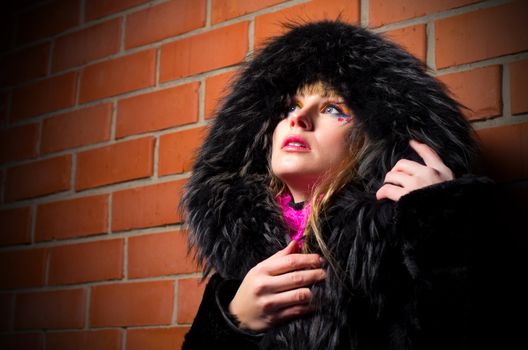 Fashion portrait of young woman on brick wall background
