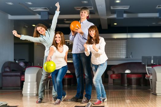 Group of young friends playing bowling, spending time with friends