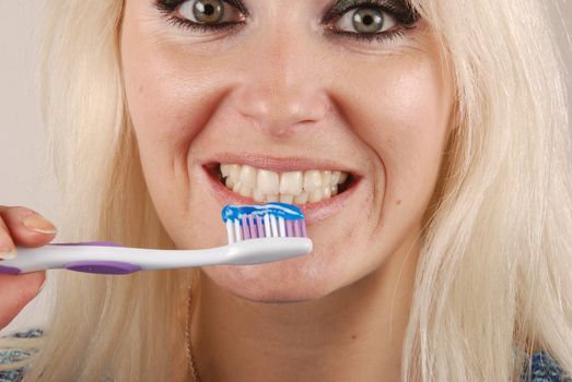 Young blonde woman brushing her teeth