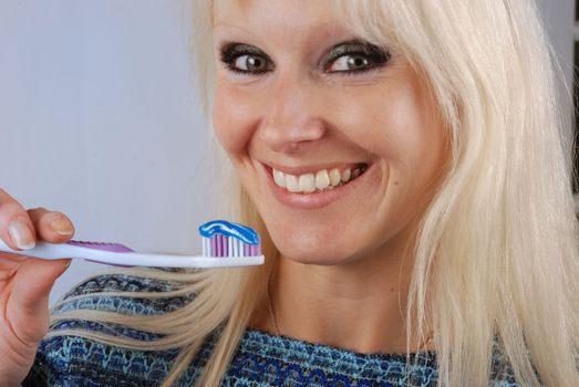 Young blonde woman brushing her teeth