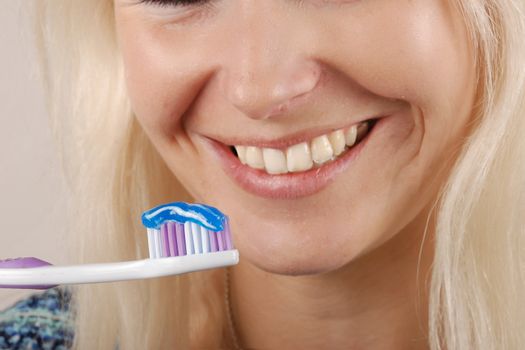 Young blonde woman brushing her teeth