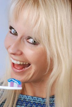 Young blonde woman brushing her teeth