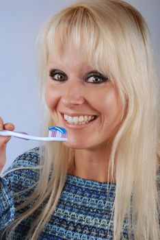 Young blonde woman brushing her teeth