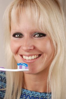 Young blonde woman brushing her teeth